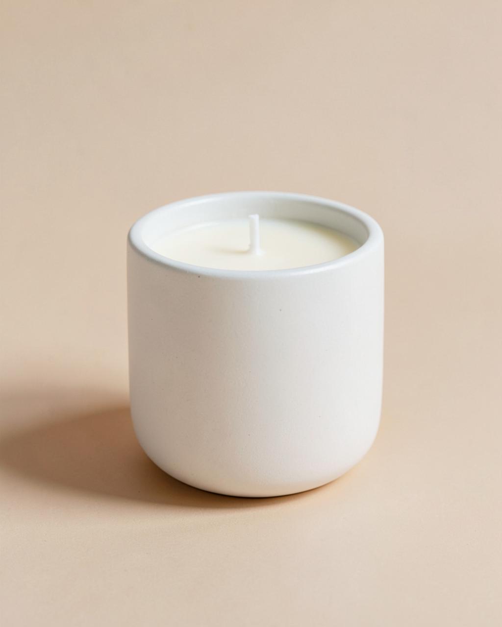 Bougie décorative blanche en contenant céramique mat sur fond beige clair