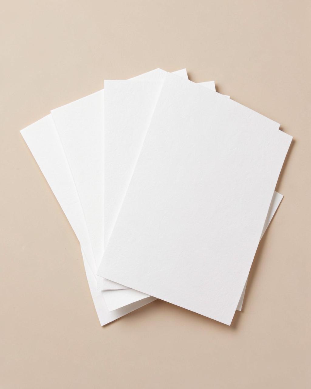 Set de cartes à écrire en papier ivoire disposées en éventail sur fond beige